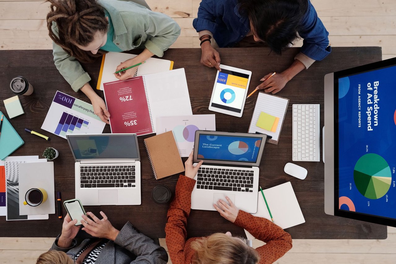 Equipe diversa trabalhando em uma estratégia de marketing digital com laptops e tablets sobre a mesa