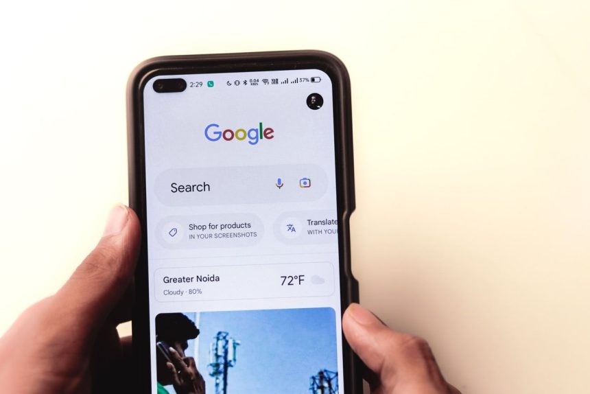 Mão segurando um smartphone com a página de busca do Google exibida na tela.