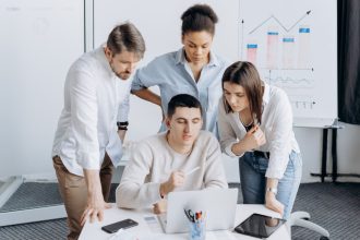 Profissionais analisam gráficos e colaboram em um projeto em um ambiente de escritório.