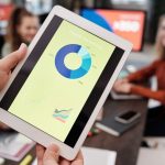 Equipe de profissionais de negócios analisa estatísticas de marketing digital em um tablet durante uma reunião.