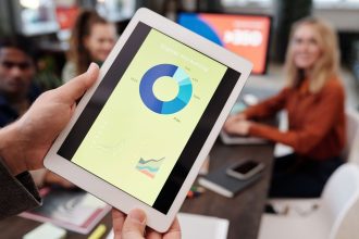 Equipe de profissionais de negócios analisa estatísticas de marketing digital em um tablet durante uma reunião.