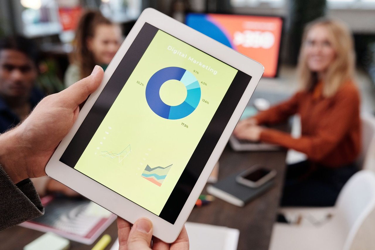Equipe de profissionais de negócios analisa estatísticas de marketing digital em um tablet durante uma reunião.