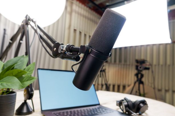 Estúdio de podcast com microfone profissional, laptop e fones de ouvido preparados para uma gravação.