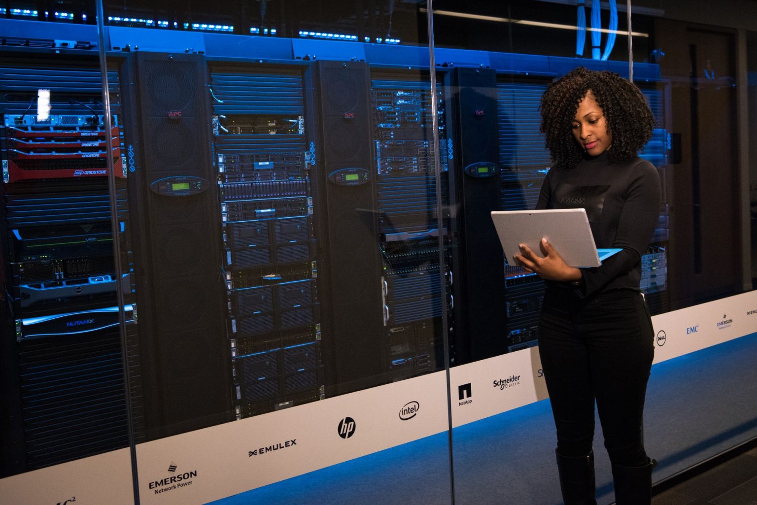 Profissional monitora servidores com um laptop em uma sala de data center.